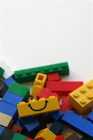 A pile of brightly colored building bricks with a smile on one of them